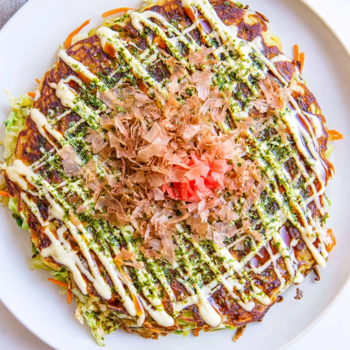 Crispy Japanese Okonomiyaki pancakes, savory with cabbage, topped with drizzled sauce and dancing bonito flakes.
