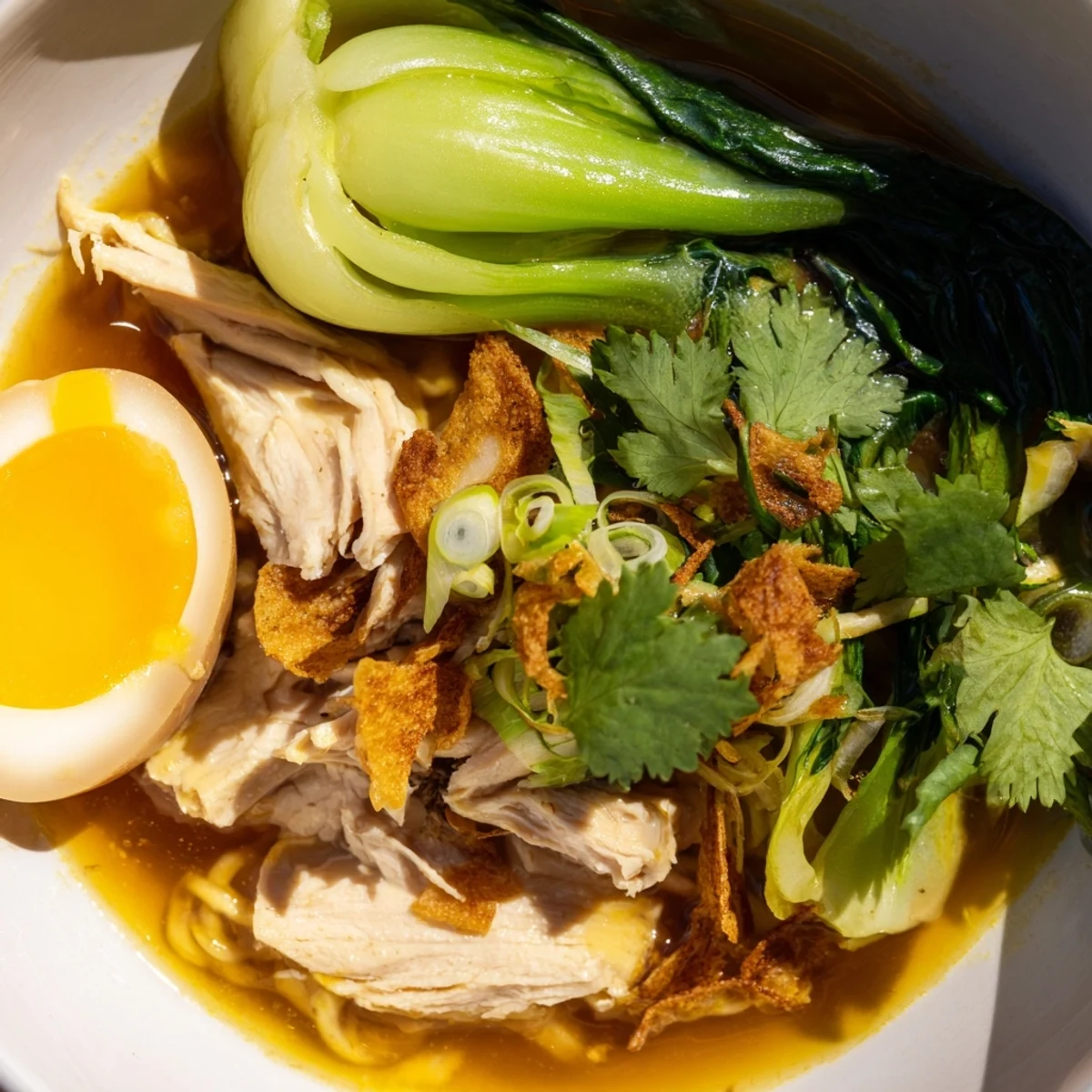 A steaming Thai Miso Ramen Bowl with tender shredded chicken, soft-boiled eggs, bok choy, and crispy shallots topped with fresh cilantro.