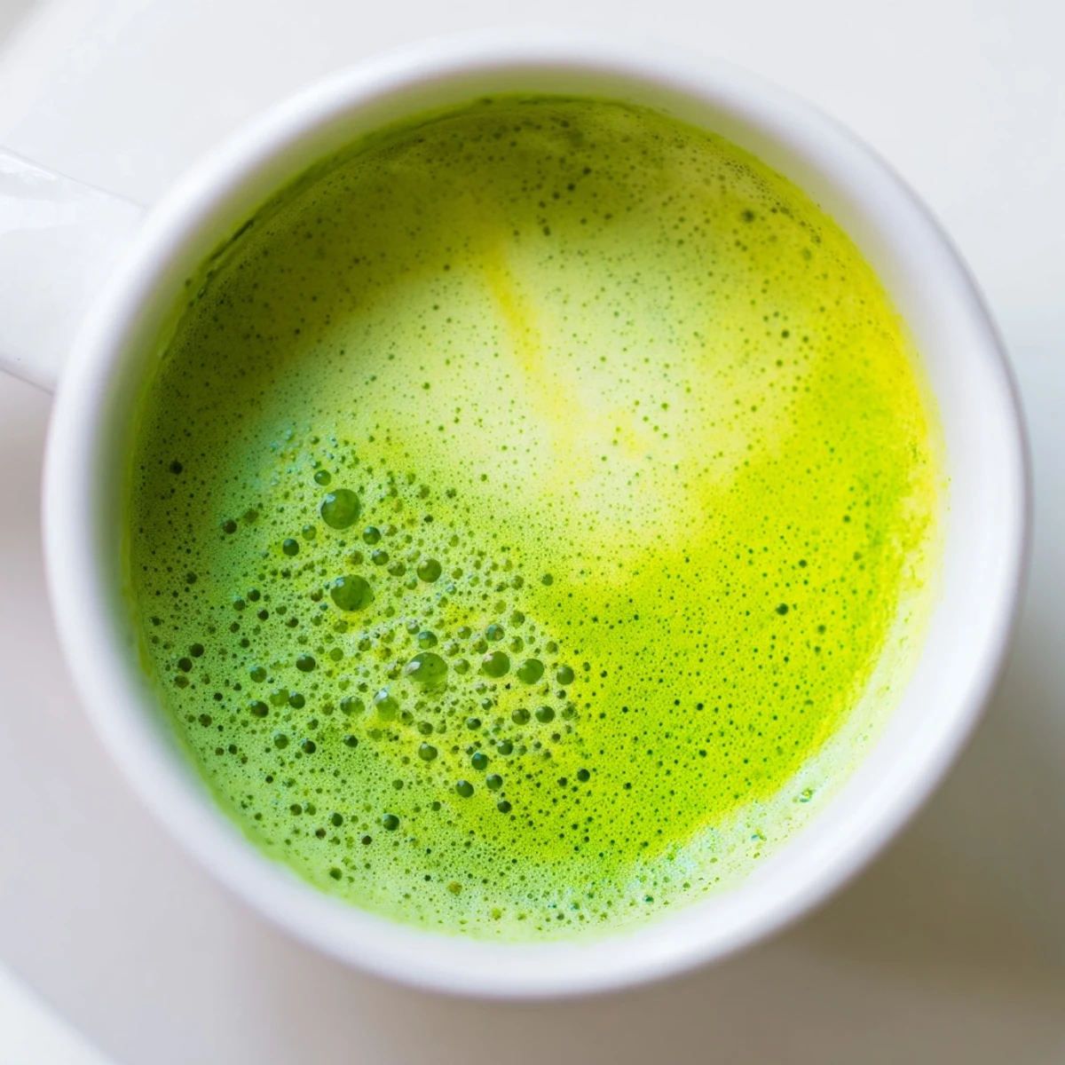 Two mugs of steaming Matcha Green Tea Latte topped with a delicate layer of foam, served as an energizing morning beverage. 