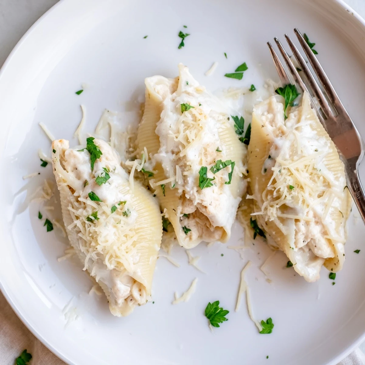 Golden-baked Chicken Alfredo Stuffed Shells, filled with creamy cheese and tender chicken, garnished with fresh parsley in a ceramic dish.