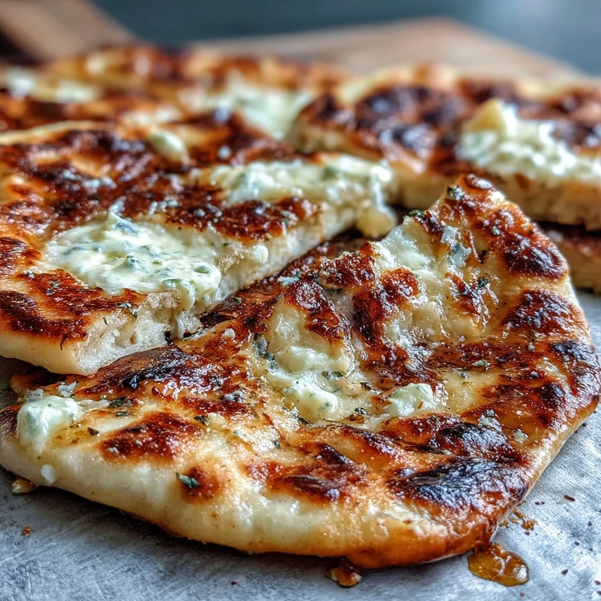 Warm, buttery The Best Easy Garlic Naan Bread stacked on a wooden board, ready to scoop up curry.