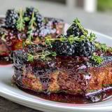 Sliced Bourbon Blackberry Pork Chops revealing a juicy center, drizzled with rich bourbon blackberry glaze.