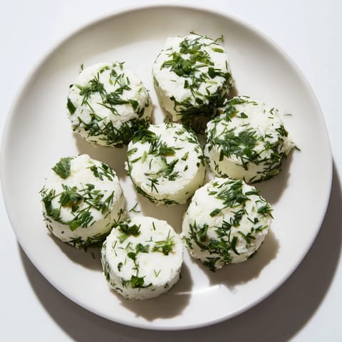 Freshly coated "The Mossy Stone" cheese rounds, green herbs creating an earthy, textured look.