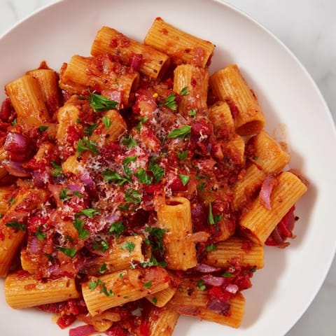 A close-up of the flavorful one-pot Diavola spicy pasta, sprinkled with fresh herbs and Parmesan.