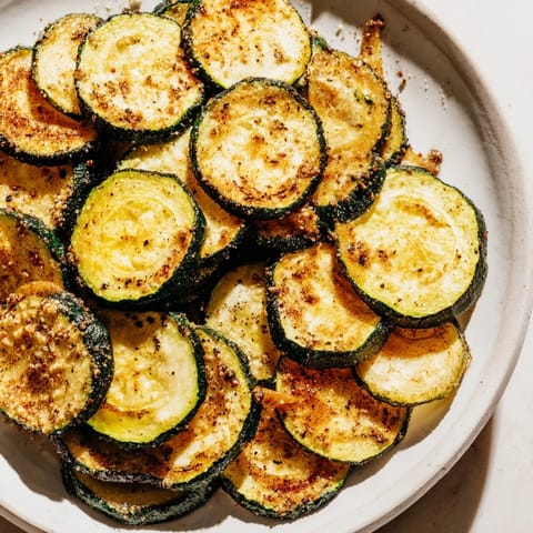 A close-up of thinly sliced zucchini chips, seasoned and baked until wonderfully golden brown.