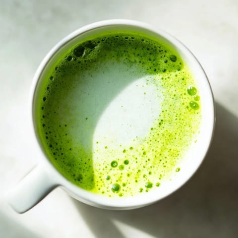A frothy Matcha Green Tea Latte with vibrant green powder whisked into a creamy steamed milk foam. 
