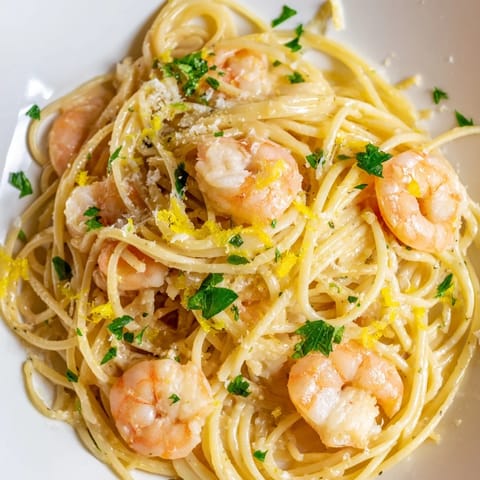 Tongs lift a portion of the Lemon Garlic Shrimp Pasta, revealing tender shrimp nestled among strands of spaghetti coated in a bright, garlic-infused lemon butter sauce.  