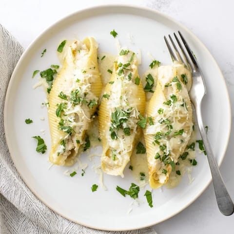 A close-up of Chicken Alfredo Stuffed Shells, with melted mozzarella and Alfredo sauce bubbling over the golden pasta tops.