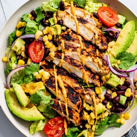 Grilled Honey Lime Chicken Taco Salad with chopped romaine, corn, black beans, avocado, and crunchy tortilla strips on a rustic plate.  