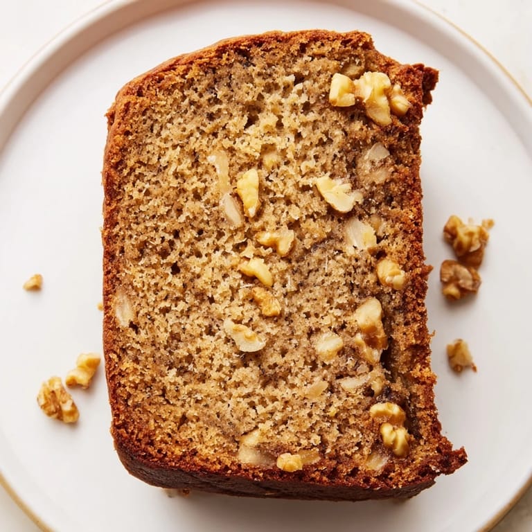 A slice of Simple Banana Bread, moist and flavorful served with a cup of hot coffee.