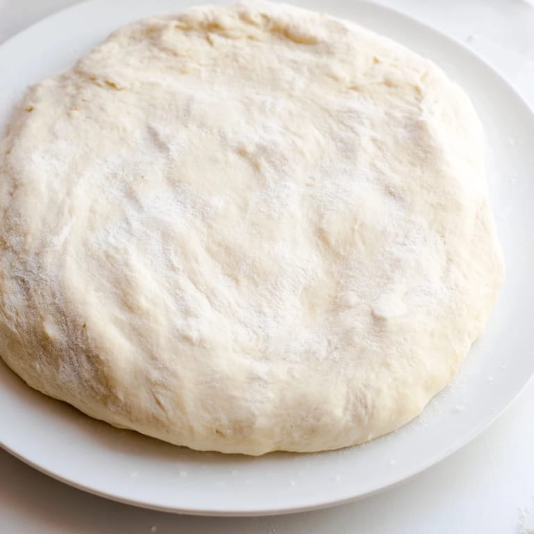 A close-up of soft Homemade Pizza Dough, showing its airy texture and perfect development after rising.