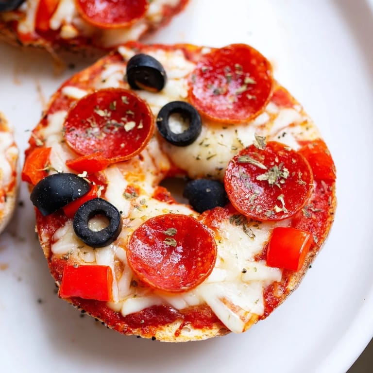 Arrangement of mini bagel pizzas, piled high with cheese and toppings for a savory treat.