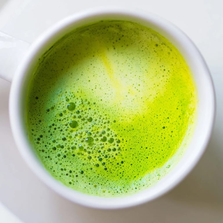 Two mugs of steaming Matcha Green Tea Latte topped with a delicate layer of foam, served as an energizing morning beverage. 