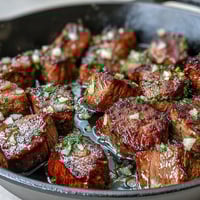 One-Pan Garlic Herb Steak Bites sizzling in a cast iron skillet, seasoned with garlic, parsley, and thyme for a savory, juicy main dish.